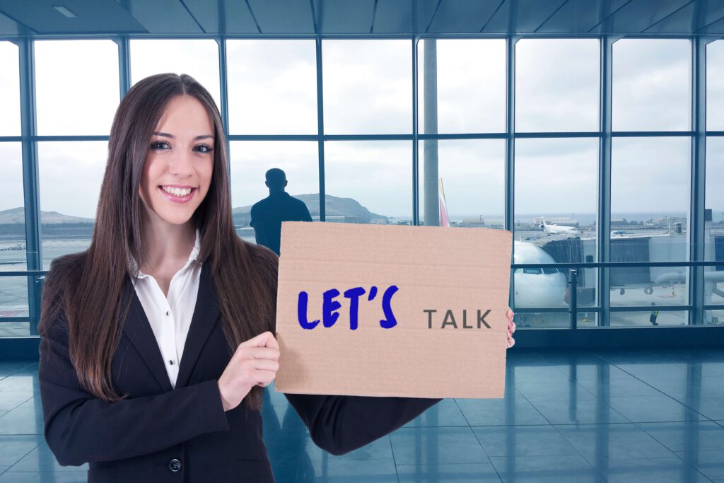 Frau am Flughafen die Schild in der Hand hält mit Lets Talk